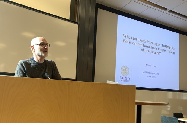 Alastair henry talking in front of a projected powerpoint presentation.