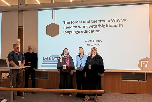 Five LAMiNATErs in front of a lit screen showing a PowerPoint presentation.