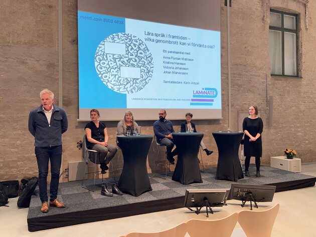 A photo of the four participants at the roundtable, the moderator and and one of LAMiNATE's platform leaders are standing at each end of the panel.