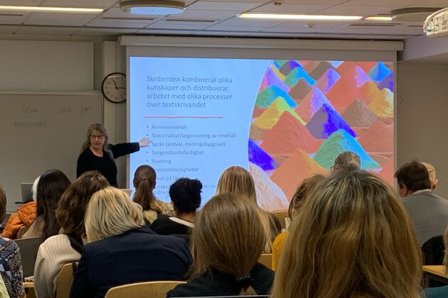 A photo of Victoria Johansson lecturing in front of a projected PowerPoint presentation.